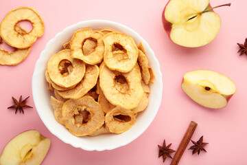 Dried apple chips with cinnamon and star anise with fresh apple. Homemade dried organic apple sliced on pink background.