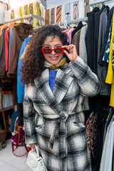 Fototapeta premium Woman looking trough sunglasses shopping in a vintage clothes store