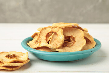 Dried apple chips in a bowl on light background.