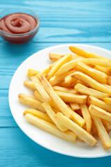 French fries with ketchup on blue background. Vertical photo