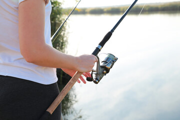 Close-up of a woman holding a fishing rod with a reel, sport fishing