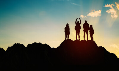 Hiking family Silhouette on top of mountain against sunset. Happy People Standing on too hill. Copy...