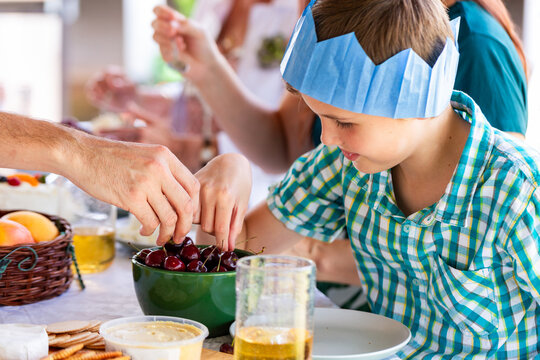 boy reaching in to bowl of fresh shiny cherries on table at christmas
