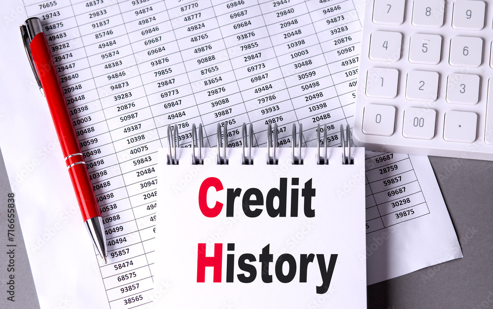 Poster credit history text on notebook with pen, calculator and chart on grey background
