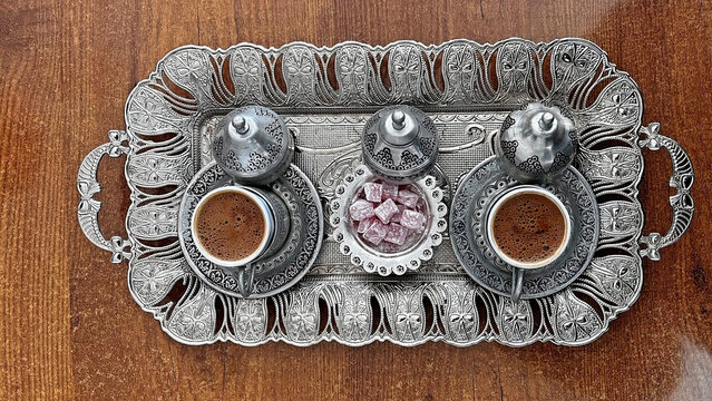 Turkish coffee served in silver trays and cups, with small Turkish delight.