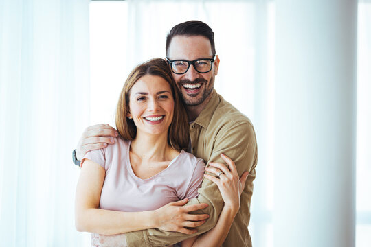 Portrait of smiling couple thinking about the future. Happy cheerful couple relaxing at home. Loving young couple embracing. Happy couple being at home, hugging,  looking lovely.