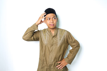 thoughtful asian muslim man thinking seriously with touching his head wearing koko clothes isolated...