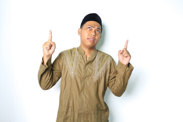 confused asian muslim man pointing to above looking up wearing koko clothes isolated on white...