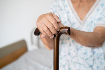 Asian elderly disability woman holding waling stick, wood cane, round handle, walking aid for help to walk.