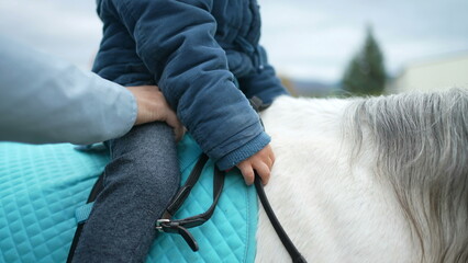 Closeup of child's hand riding pony, 4 year old boy on horseback