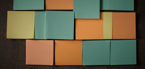  a close up of a wall made out of different colored pieces of paper with a brown background and a black wall in the middle of the room with a brown floor.