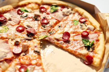 A freshly baked pizza with sliced tomatoes, cheese, mushrooms, and herbs is missing two slices,...
