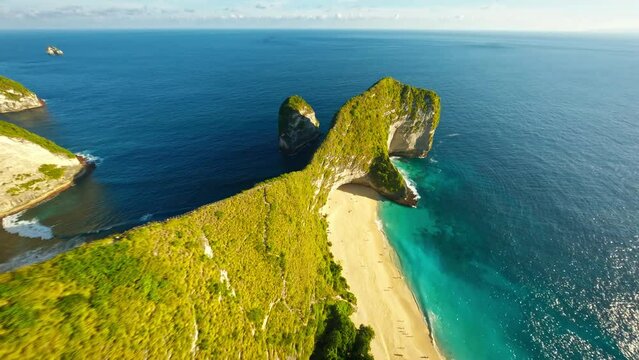 Famous Kelingking T-Rex sightseeing spot landmark at Nusa Penida Island, Bali, Indonesia. Aerial FPV drone footage at daytime with beautiful waves