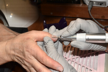 A manicurist works with a milling cutter on a clients nails.