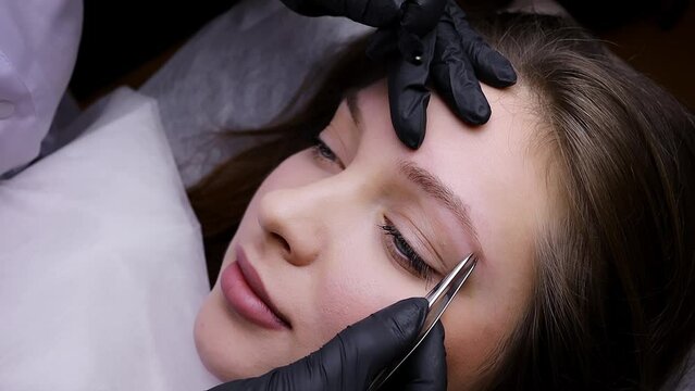 Preparation of the model's eyebrows for the procedure of permanent makeup. Permanent makeup procedure, performing PMU of eyebrows