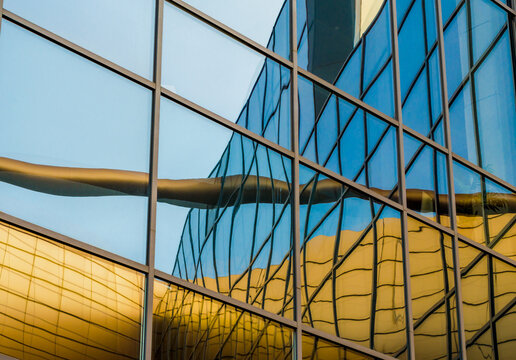 distorted reflection of a yellow building in the mirrored windows of an office building