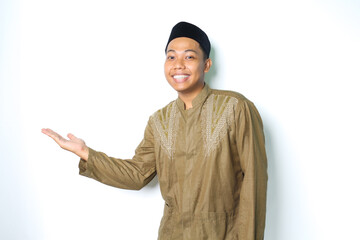 happy asian muslim man wearing koko clothes presenting to beside with open palms isolated on white...