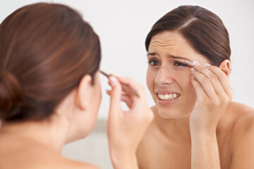 Eyebrow, plucking and woman with pain for beauty, self care and mirror in bathroom. Makeup, routine...