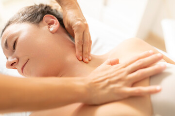 A patient, completely relaxed, enjoys receiving a massage from her physiotherapist in the neck area
