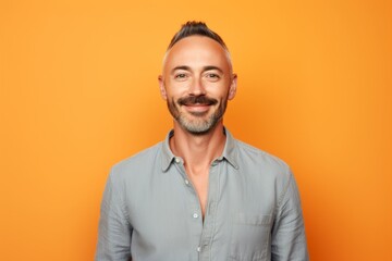 Obraz premium Portrait of a tender man in his 30s sporting a versatile denim shirt against a pastel orange background. AI Generation