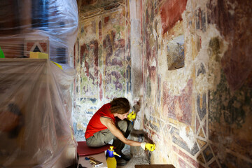 Female Restorer Cleaning An Ancient Fresco With a Scalpel as Part of Renovation Process - Smihel,...