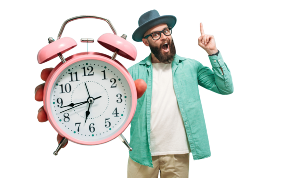Young crazy bearded charismatic hipster holding a closeup of a huge pink alarm clock pointing at it isolated. It's time to.