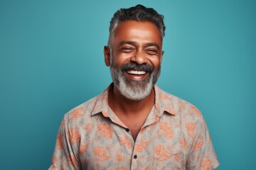 Obraz premium Portrait of a satisfied indian man in his 50s donning a trendy cropped top against a pastel teal background. AI Generation
