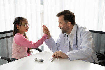 Patient Asia kid girl meeting and hi five caucasian doctor at hospital	
