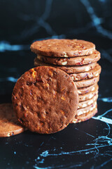 A stack of chocolate shortbread with fruits and nuts on marble background