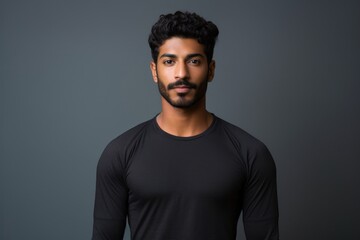 Obraz premium Portrait of a content indian man in his 20s showing off a lightweight base layer against a soft gray background. AI Generation