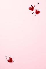 Red hearts and confetti in corners on pink vertical background. Valentine's Day poster design.