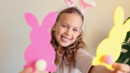 Close up hands child girl holds paper colored garland Easter bunny pompons. Excited emotional...