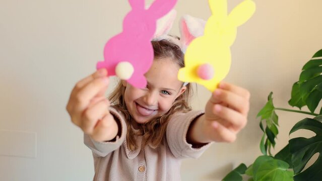 Close up hands child girl holds paper colored garland Easter bunny pompons. Excited emotional children. Rabbit years crafts for Easter party at home. Holiday Art Activity Kid. creativity hobby DIY