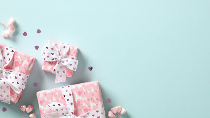 Valentine's Day banner with pink gifts decorated ribbon bow and confetti on turquoise background.