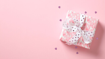 Pink gift box with ribbon bow and hearts on pastel pink background. Flat lay, top view. Happy Valentine's Day concept.