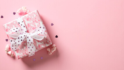 Valentine's Day gift box with hearts on pink background.
