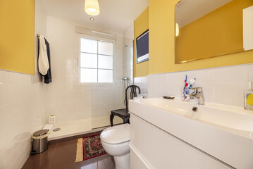 Modern design bathroom with mirror integrated into the wall with bevels, furniture with white drawers