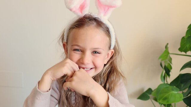 Easter, holidays, spring concept - happy, funny, smiling, adorable little toddler girl wearing bunny ears headband. Child smile with teeth. Excited emotional kid in rabbit costume. Positive emotions
