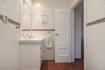 Fototapeta na wymiar Small modern design bathroom with white wooden furniture with porcelain sink, terracotta flooring