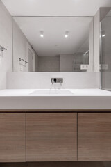 A modern design bathroom with an integrated mirror that runs along the entire wall, a straight one-piece porcelain sink