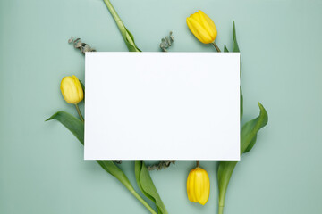 Empty white paper blank, flowers on green background. Wedding branding mock up. Top view. Copy space