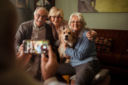 Senior friends with dog posing for a photo at home