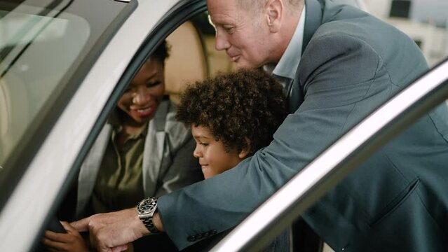 Multiethnic family testing out car at dealership