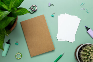 Creative flat lay mockup design of workspace. Top view composition with white to do list, succulents and stationery on green background