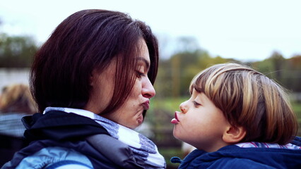 Mother and child peck kiss in authentic caring parent and child relationship. mom holding small son...