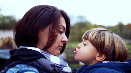 Mother and child peck kiss in authentic caring parent and child relationship. mom holding small son in arms