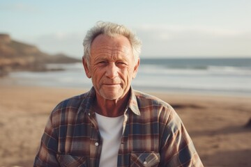 Portrait of a tender man in his 80s dressed in a relaxed flannel shirt against a sandy beach background. AI Generation - obrazy, fototapety, plakaty