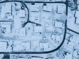 Aerial view of suburban neighborhood with snow covered roofs and streets. Small town in winter time in Switzerland, Europe.