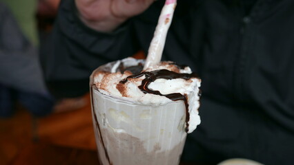 Person drinking milkshake with plate of pancakes. Man indulging in sugarily food at restaurant enjoying decadent dessert