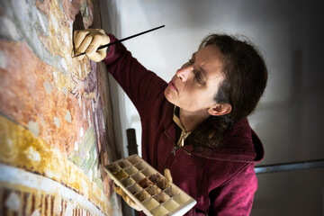 Skilled and Confident Female Restorer Painter Restoring Work on an Ancient Fresco in a Church in...
